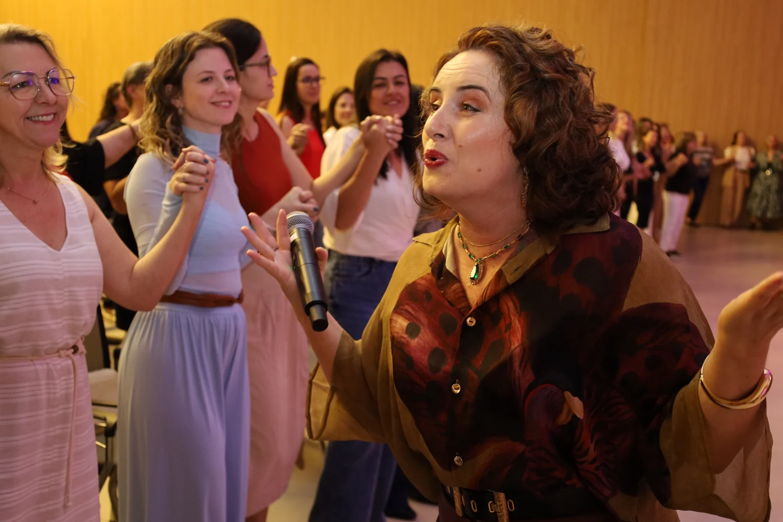 Taty Dal Bem falando ao microfone durante uma vivência do Mulheres de Valor